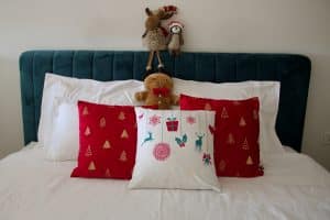 Cama decorada con cojines y juguetes navideños.