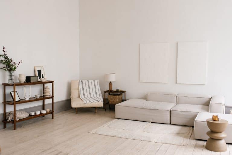 Salón escandinavo minimalista y moderno con sofá blanco, sillón y alfombra.