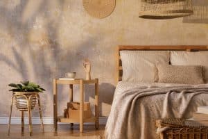 Elegante dormitorio con mesa de centro de diseño, muebles, plantas, alfombra, decoración de ratán y elegantes accesorios personales. Bonitas sábanas, mantas y almohadas de color beige. Plantilla.