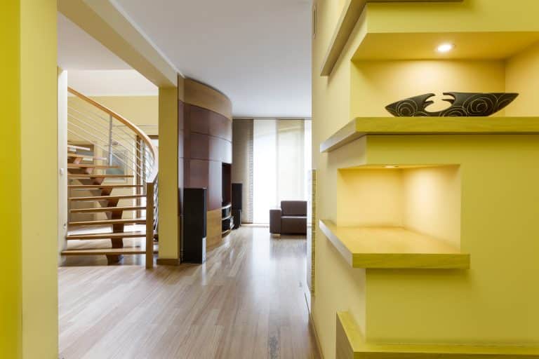 Vivid hall with lemon walls and fitted shelves, opening to stairway