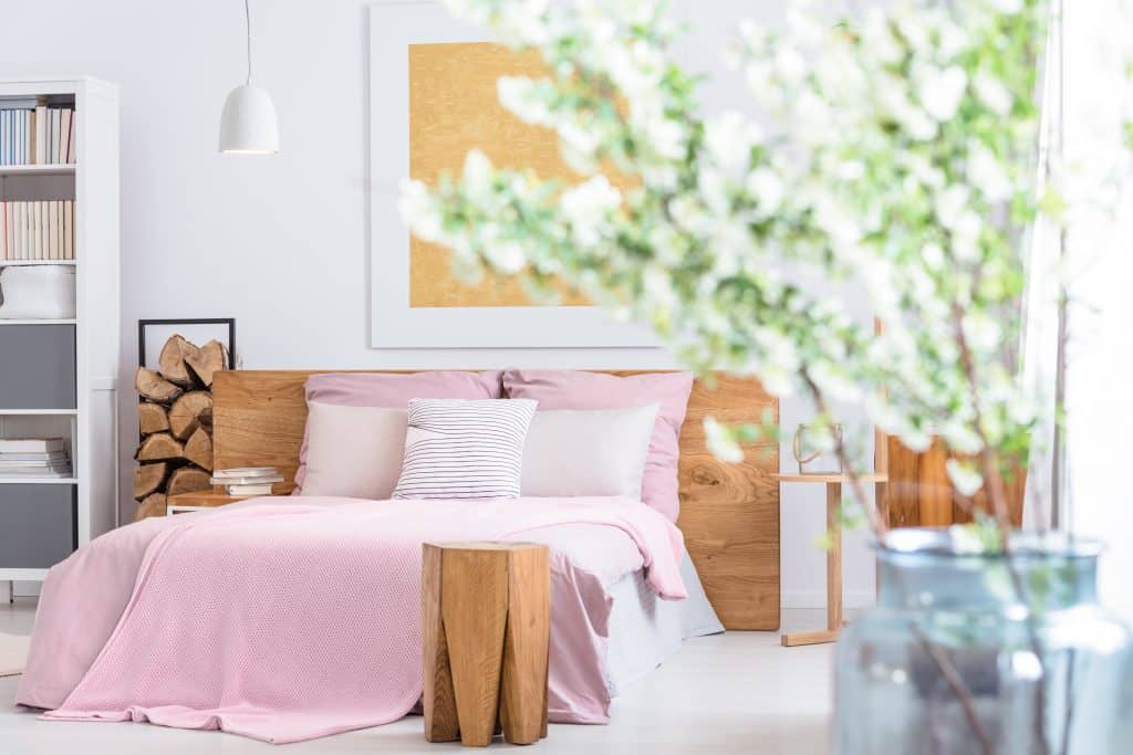 Jarrón de cristal con flores en un dormitorio clásico con cama extragrande