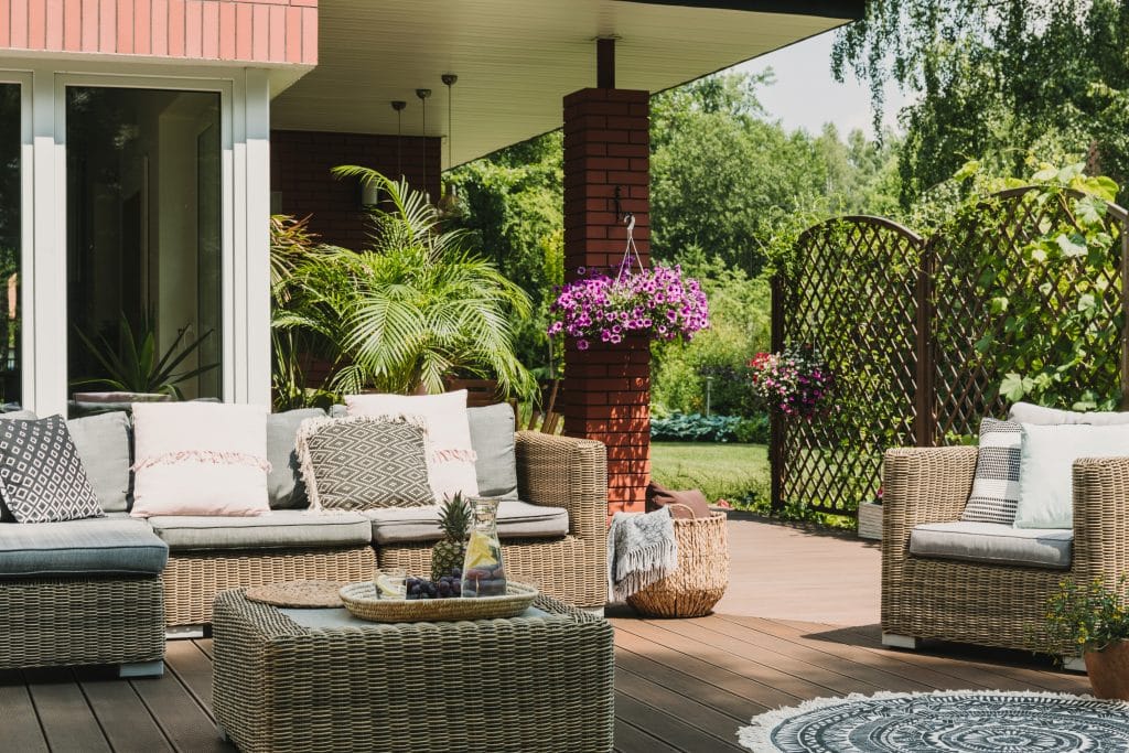 Muebles elegantes en una terraza de madera situada en un precioso jardín verde