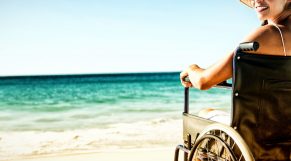 Wheelchair woman sitting smiling at camera on the beach